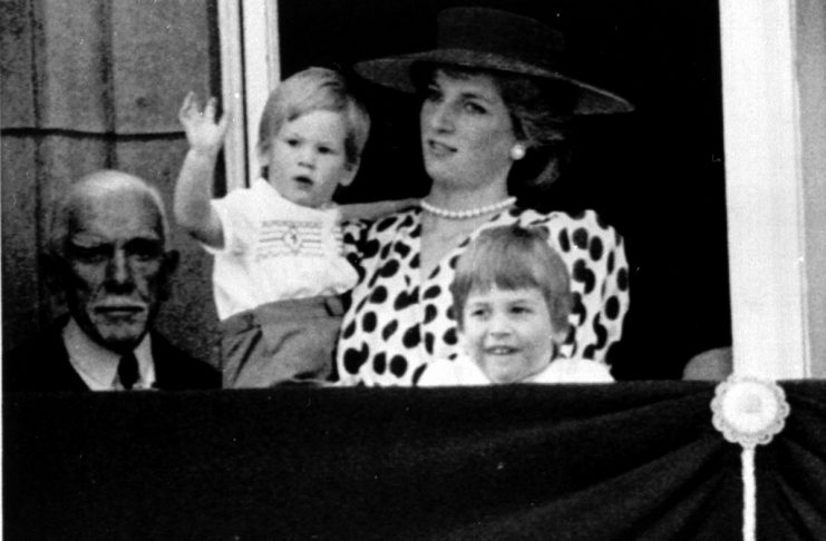 Britain’s late Princess Diana (2nd R) holds Prince Harry (2nd L) as he waves to the crowd from the b..