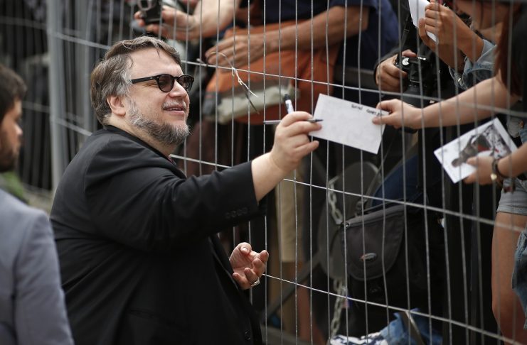 Jury member film director Guillermo del Toro signs autographs to cinema fan as he arrives to attend a photocall before the opening of the 68th Cannes Film Festival in Cannes