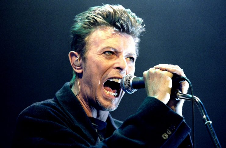 British Pop Star David Bowie screams into the microphone as he performs on stage during his concert in Vienna