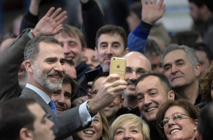 Spain’s King Felipe VI takes a selfie with a group of farmers and workers during a visit to a dairy products company in Siero