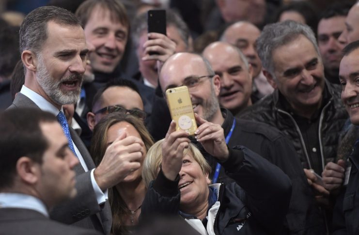 Spain’s King Felipe VI takes a selfie with a group of farmers and workers during a visit to a dairy products company in Siero