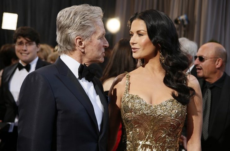 Actor Michael Douglas talks with his wife, actress Catherine Zeta-Jones, at the 85th Academy Awards in Hollywood