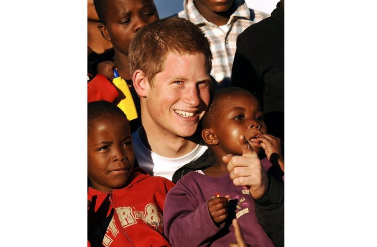 – PHOTO TAKEN 24APR06 – Britain’s Prince Harry (C) hold children Mutsu (L) and Lintle (R) in the gro..
