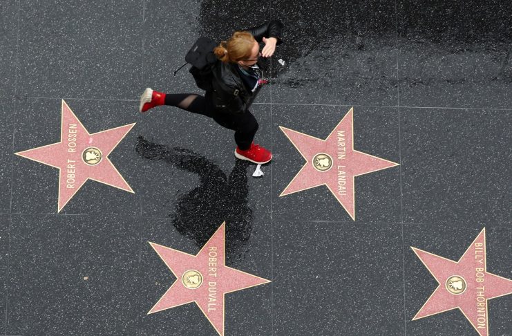 A woman runs on the Hollywood Walk of Fame in the rain in Hollywood, Los Angeles