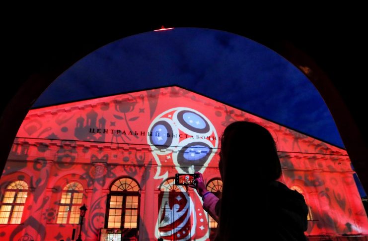 A woman takes pictures of Moscow’s Manezh building during a preview of laser show devoted to 2018 FIFA World Cup in Moscow