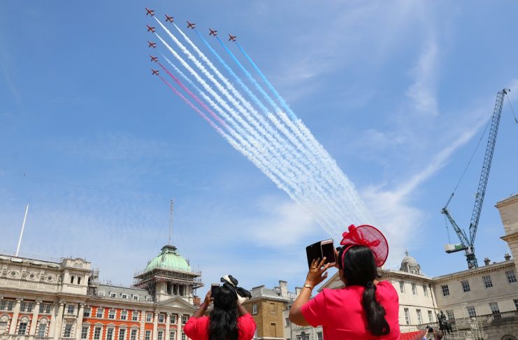 Members of the public photograph the Red Arrows display team as part of an RAF flypast for Trooping the Colour in central London