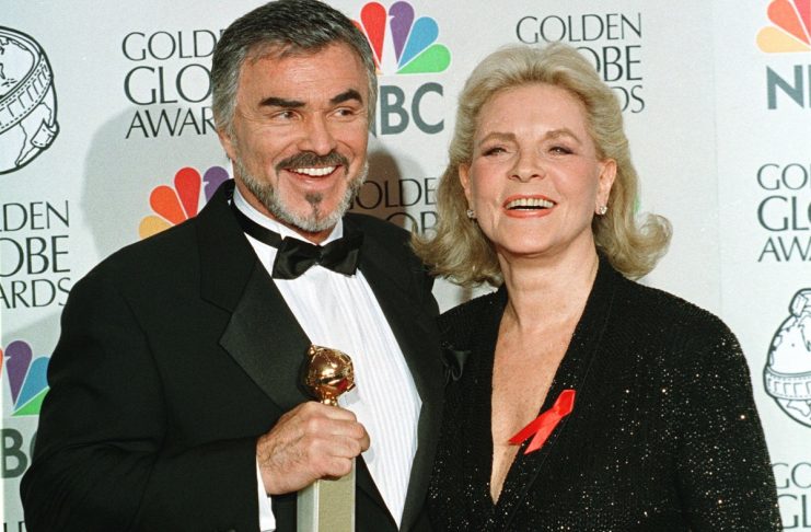 Burt Reynolds and actress Lauren Bacall pose for photographers as Reynolds holds his Golden Globe th..