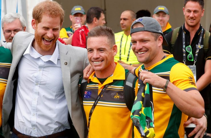 Britain’s Prince Harry reacts as he poses with Australian athletes taking part in the Invictus Games as Benjamin Yeomans holds up swimwear he wanted to present to the prince at the Royal Botanic Garden in Sydney