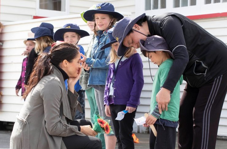 Meghan Markle the Duchess of Sussex talks with schoolboy Joe Young (R, green jumper) and other children outside the Maranui Cafe in Wellington