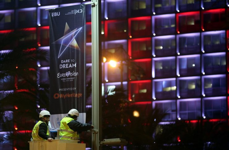 Labourers stand on a crane as they hang 2019 Eurovision Song Contest banners in Tel Aviv, Israel