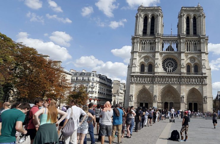 Tourists queue as they wait to visit the Notre Dame Cathedral on a warm summer’s day in Paris